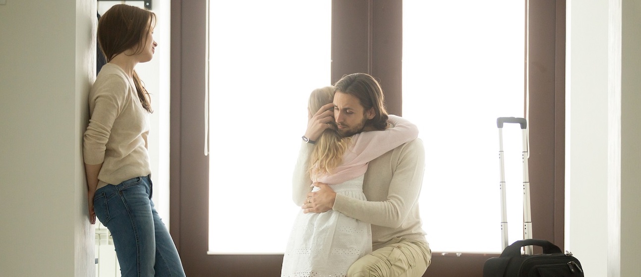 Father hugging a daughter with a suitcase nearby, signifying he is leaving