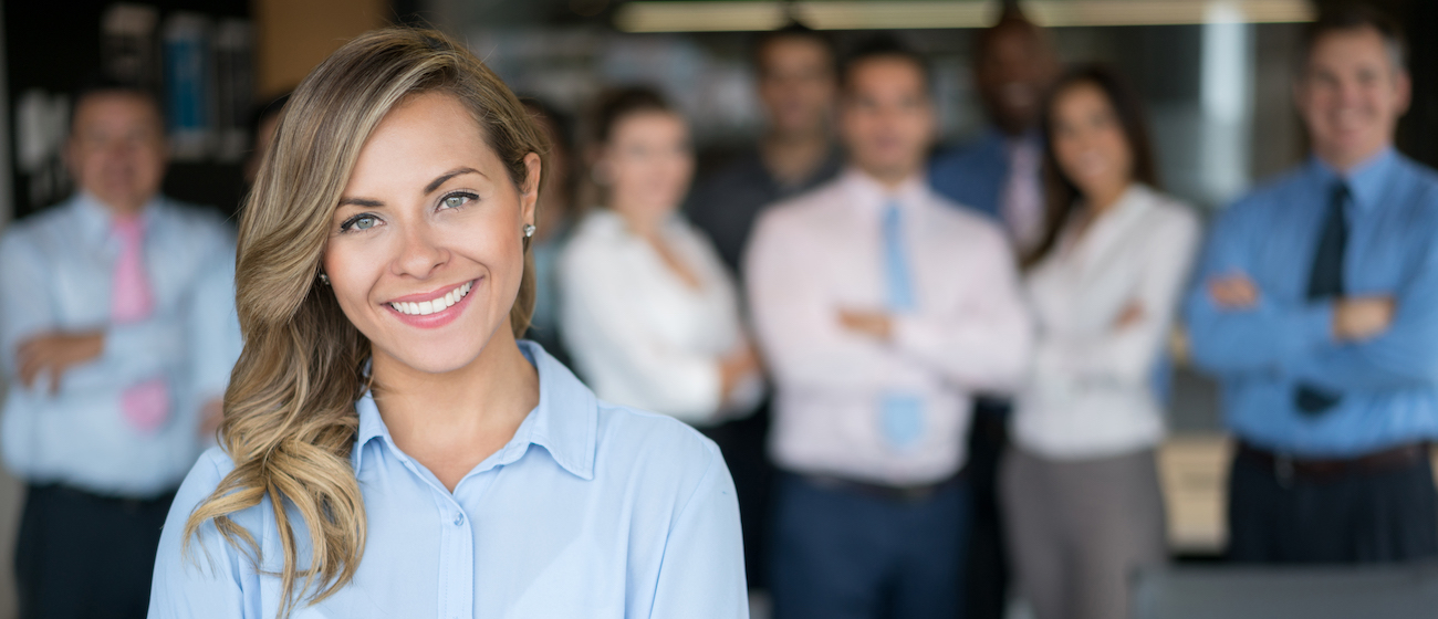 Successful business woman leading a group and looking at the camera at the office. Business acquisitions and sales.